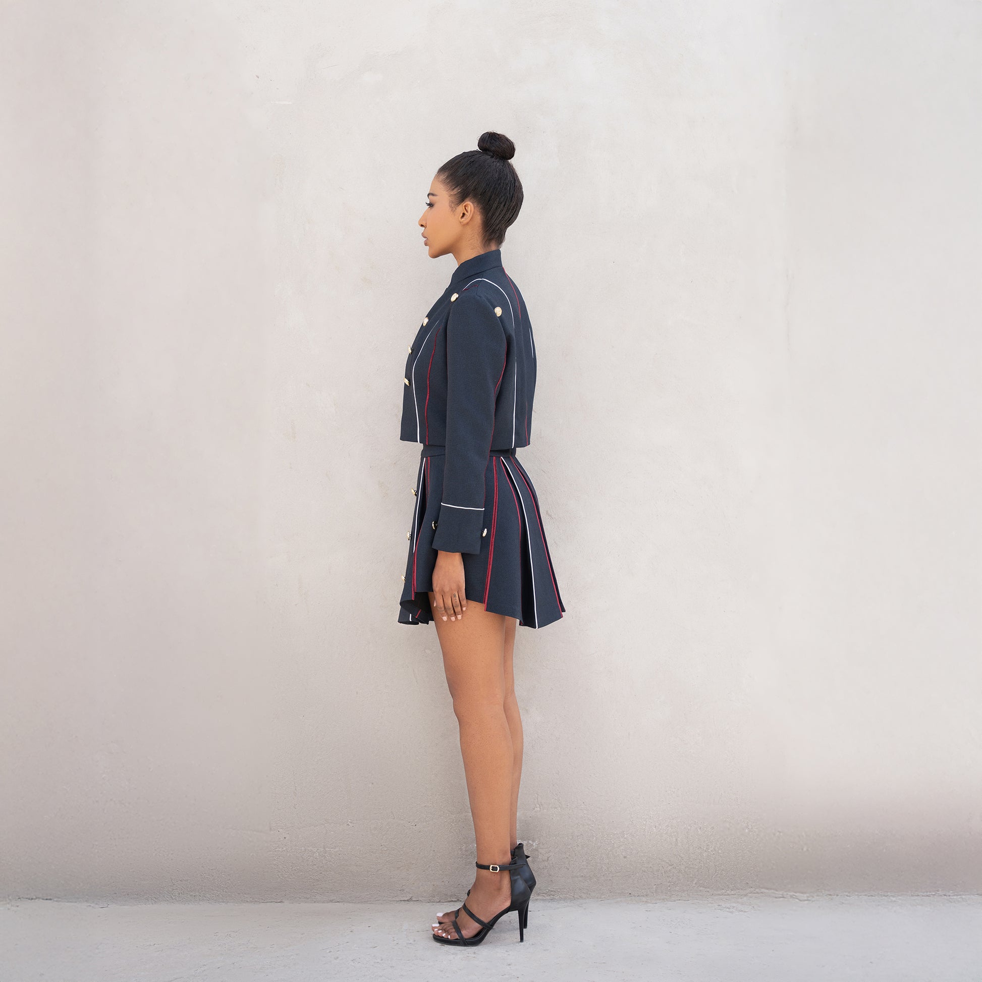 Side profile of the Axis set, highlighting the tailored jacket fit and pleated skirt structure.