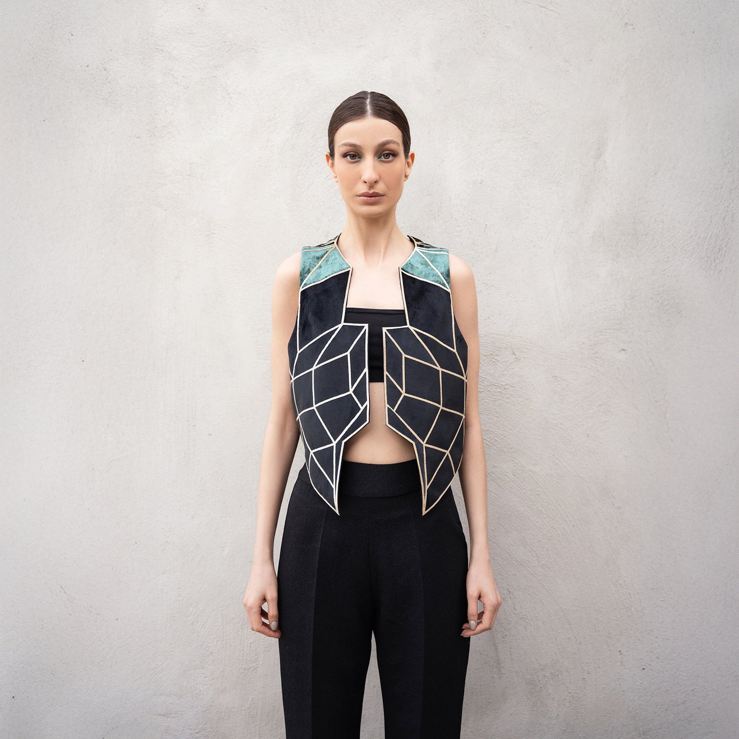 Close-up of the Panther Facad vest, highlighting the golden laser-cut geometric front design and green velvet shoulder panels.