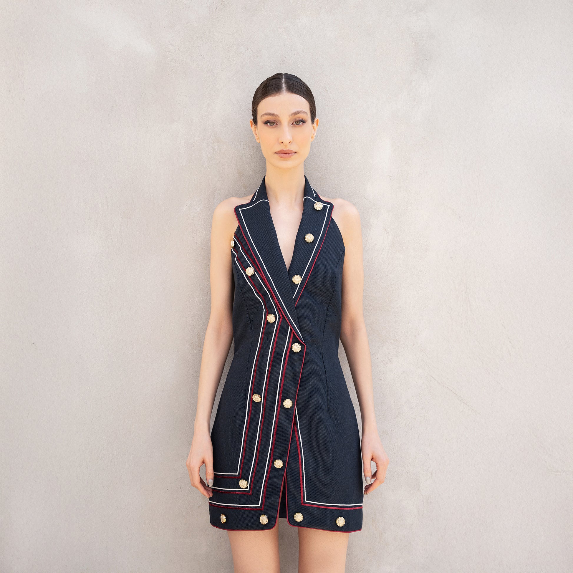 Close-up of the Pulse dress, highlighting the double-breasted sleeveless cut, golden buttons, and structured laser-cut line design.